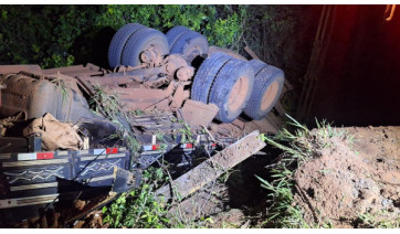 Caminhão com 15 toneladas de mandioca cai em córrego durante travessia em ponte de madeira